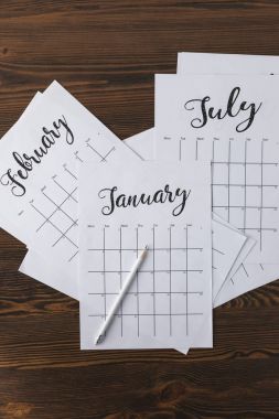 flat lay with arranged calendar papers and pencil on wooden tabletop clipart