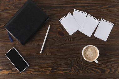 düz lay smartphone, defter, kalem ve ahşap masa üzerinde kahve ile