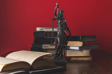 opened juridical books with lady justice statue on wooden table, law concept clipart