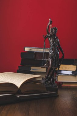 opened juridical books with lady justice statue on wooden table, law concept clipart