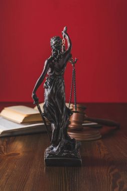 opened juridical books with lady justice statue on wooden table, law concept clipart