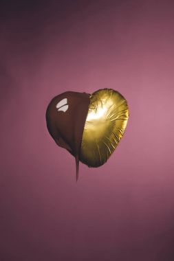 heart shaped candy in golden wrapper with liquid chocolate isolated on pink