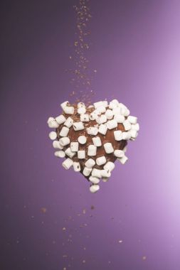 chocolate heart shaped candy with marshmallow and falling crumbled chocolate isolated on purple clipart