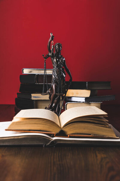открытые юридические книги со статуей леди правосудия на деревянном столе, юридическая концепция
