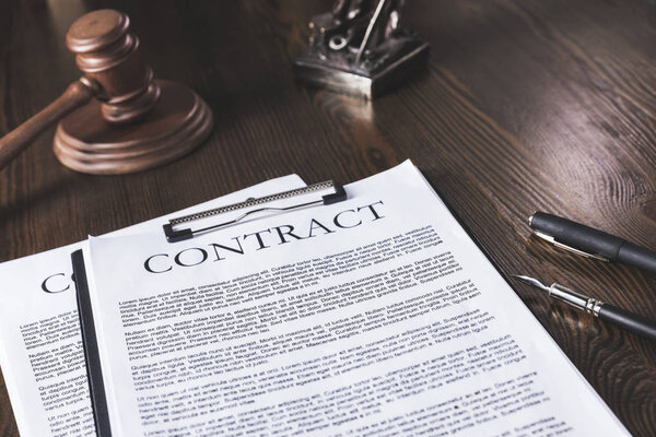 juridical contract on wooden table with pen and hammer, law concept