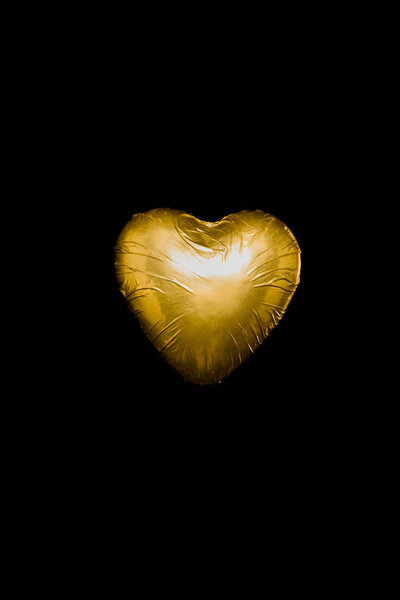 heart shaped candy in golden wrapper isolated on black