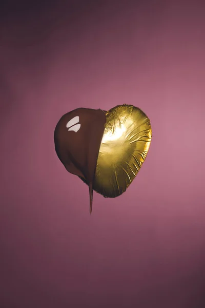 心形糖果的金色包装与液体巧克力隔离粉红色 — 图库照片
