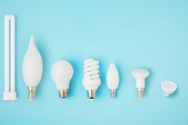 flat lay with arranged various light bulbs isolated on blue clipart