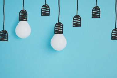 close up view of white lamps pretending hanging on lamp holders isolated on blue clipart