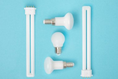 flat lay with arranged various light bulbs isolated on blue clipart