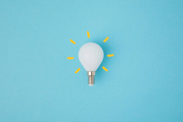 close up view of white light bulb with yellow lines isolated on blue