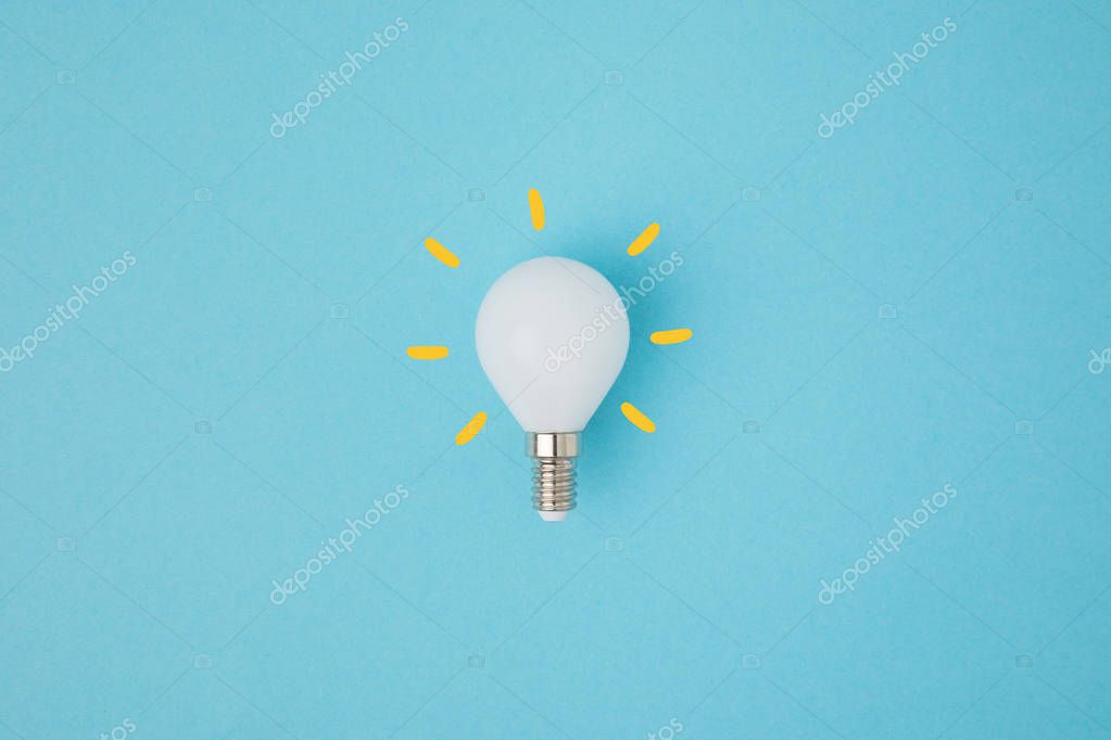 Close up view of white light bulb with yellow lines isolated on blue