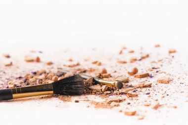 Beyaz yüzeyinde kozmetik tozu ile yalan makyaj fırçaları
