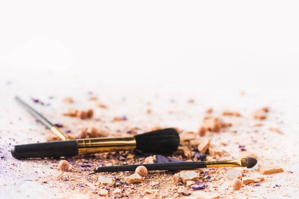 cosmetic powder with makeup brushes on white surface