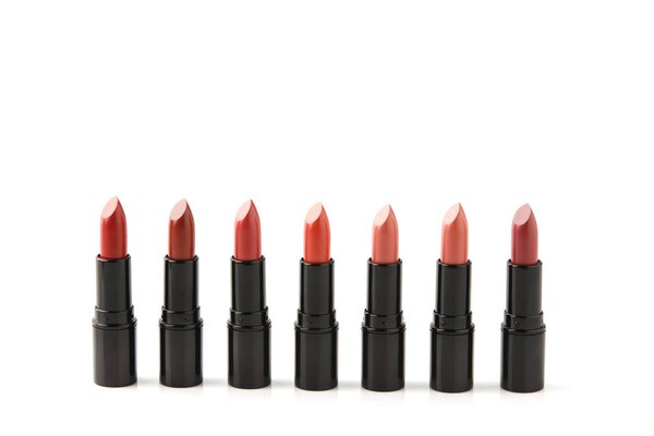 row of red lipsticks of various shades isolated on white