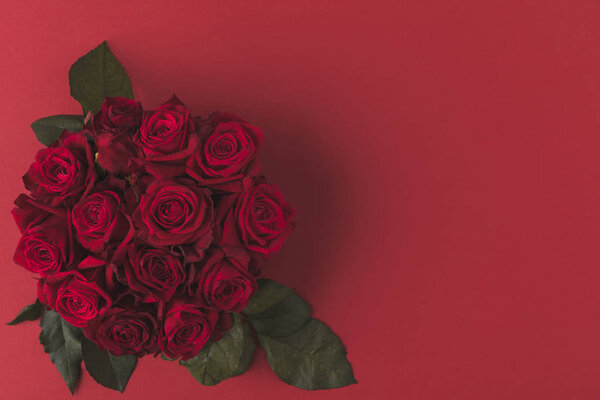 top view of bouquet of red roses with green leaves isolated on red