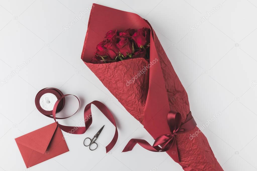 flat lay with bouquet of roses, ribbon and envelope isolated on white, st valentines day holiday concept