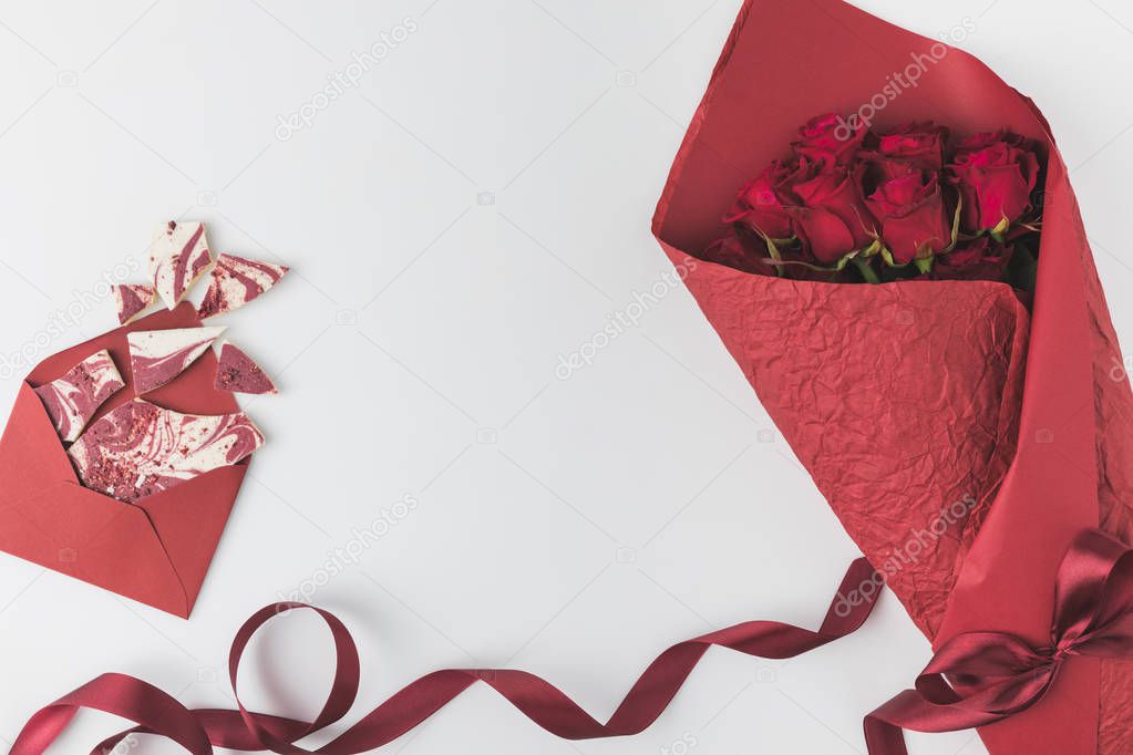 flat lay with arrangement of bouquet of red roses with ribbon and envelope with sweet dessert isolated on white, st valentines day concept