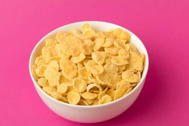 close-up view of white bowl with sweet healthy corn flakes isolated on pink  clipart