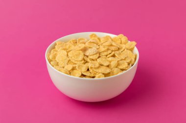 close-up view of white bowl with sweet tasty corn flakes isolated on pink  clipart