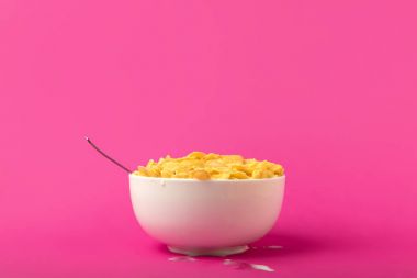 close-up view of white bowl full of sweet tasty corn flakes and spoon isolated on pink clipart