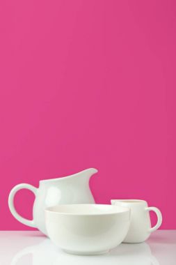 close-up view of empty white bowl, big jug and milk jug on pink  clipart
