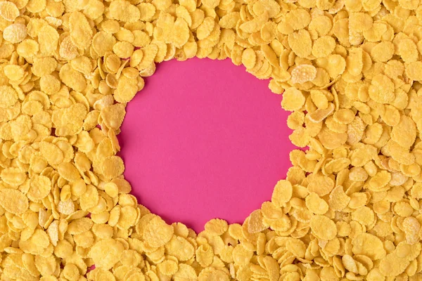 在粉红色的健康有机玉米片上的圆圈的顶部视图 — 图库照片