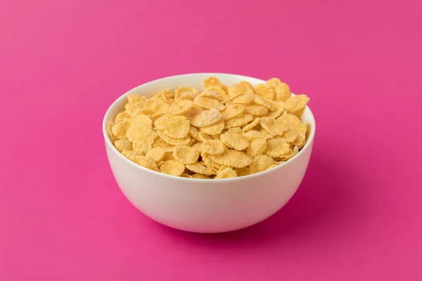 白色碗的近距离观看与甜可口玉米片被隔绝在粉红色 — 图库照片