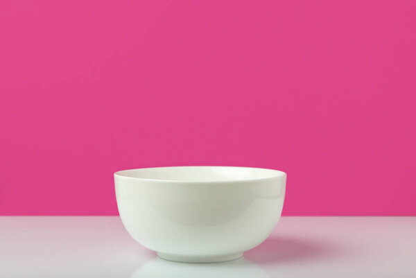 close-up view of single empty white bowl ready for breakfast on pink