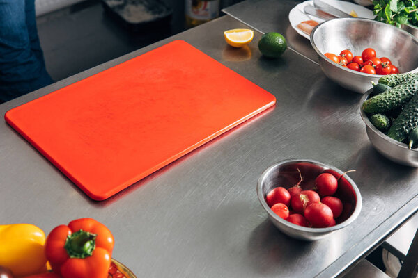 cutting board and fresh vegetables at restaurant kitchen