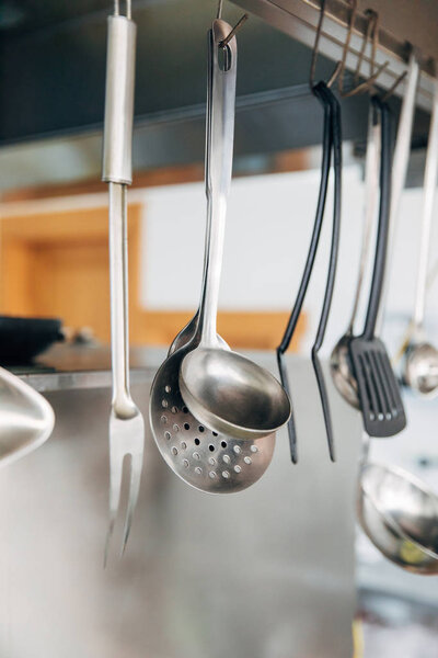 close-up shot of metallic utensils hanging at kitchen of restaurant