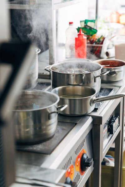 various dishes cooking in sauce pans at restaurant kitchen
