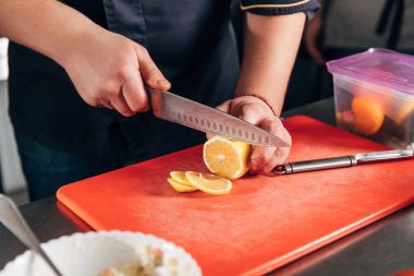 cropped shot of chef slicing lemon at restaurant clipart