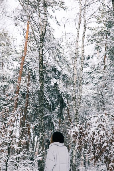 back view of woman walking in snowy forest