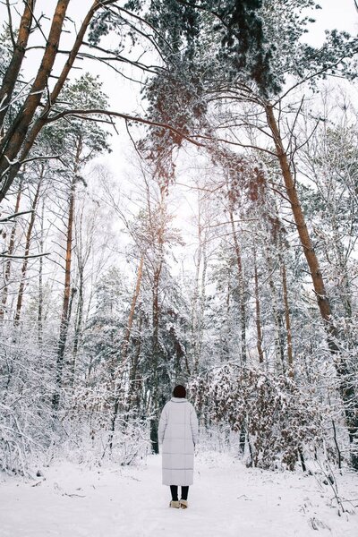 rear view of girl walking in snowy forest