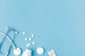 container, scattered pills and stethoscope isolated on blue background   