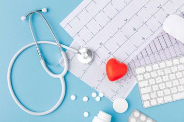 stethoscope, paper with cardiogram, scattered pills, red heart and keyboard isolated on blue background   clipart