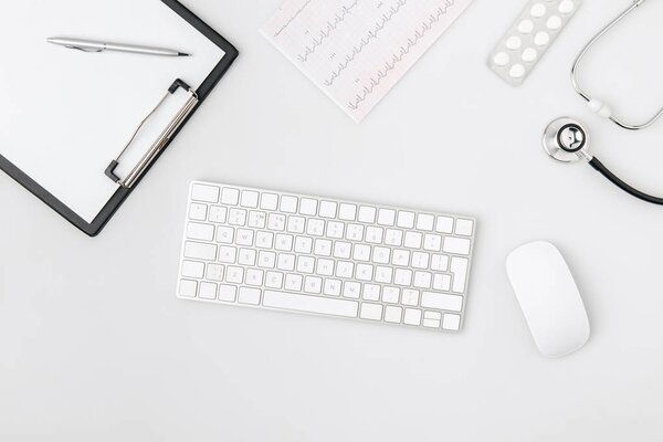 keyboard surrounded by paper in folder, computer mouse, stethoscope isolated on white background   