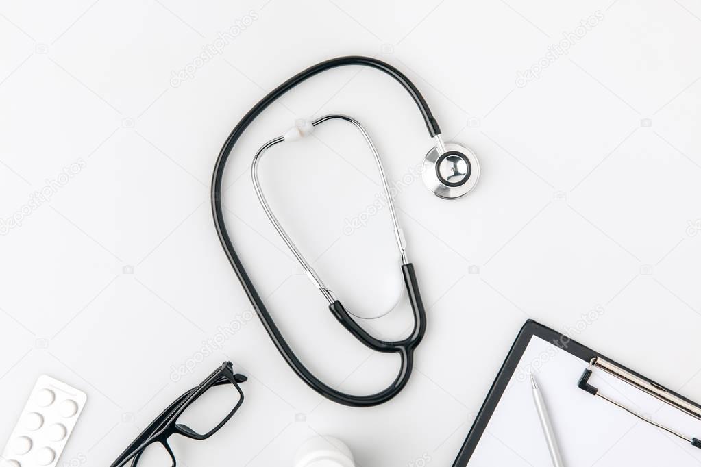 stethoscope near glasses and paper in folder laying isolated on white background    