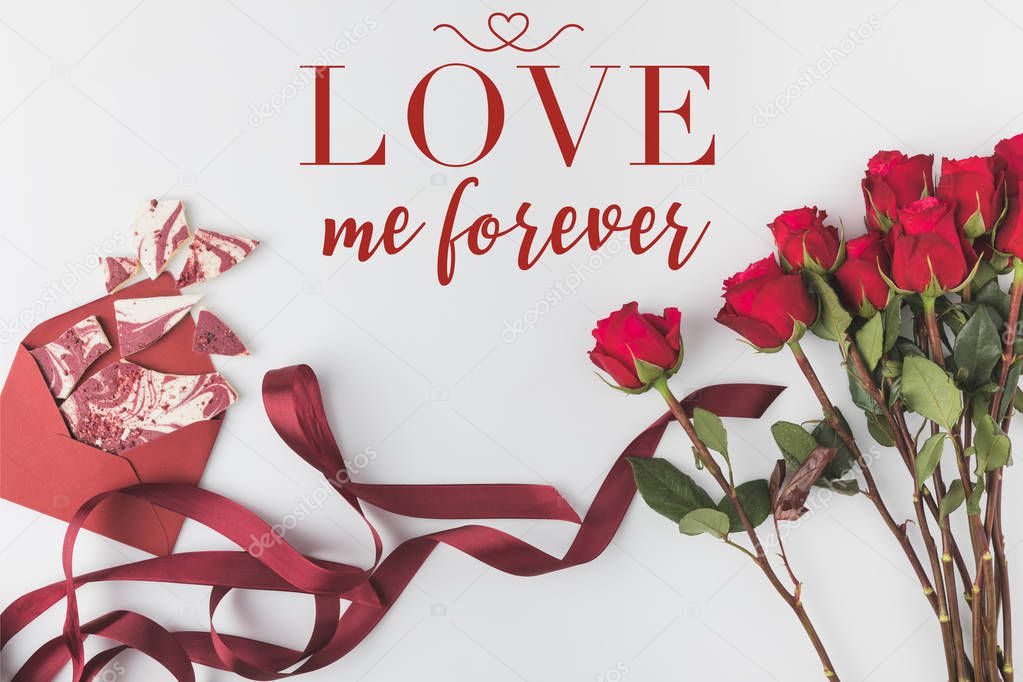 flat lay with arrangement of red roses with ribbon and envelope with sweet dessert isolated on white, st valentines day concept