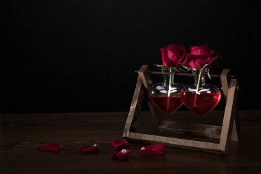 kalbinde iki kırmızı gül vazo ahşap stand ve yaprakları tablo şeklinde