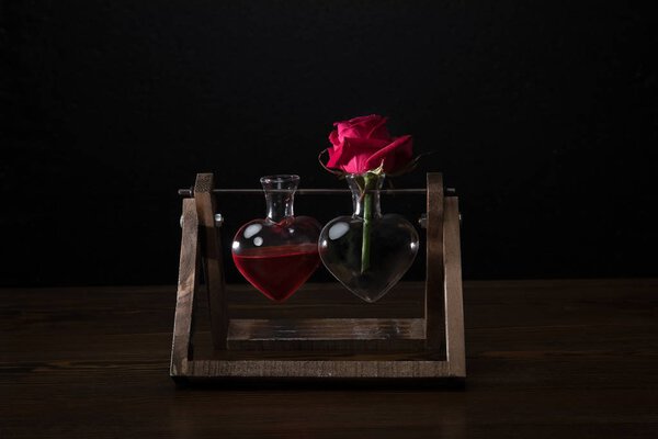 red rose in heart shaped vase and vase with love elixir