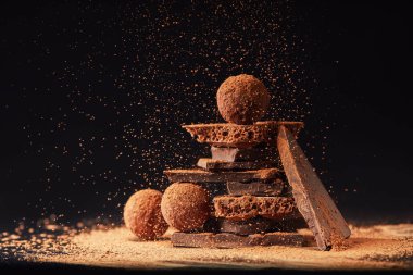 siyah üzerine kakao tozu ile domalan ve çikolata bar düzenlemenin görünümü kadar kapatın
