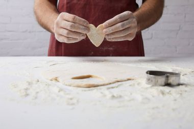cropped image of chef holding heart shaped piece of dough in hands, valentines day concept