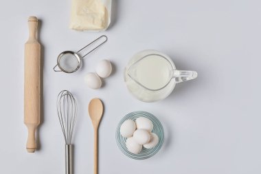 top view of eggs and milk on white table clipart