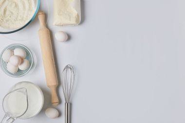 Beyaz masa üzerinde yumurta, süt ve oklava Üstten Görünüm