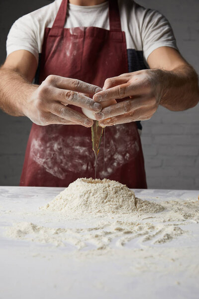 cropped image of chef preparing dough and adding egg