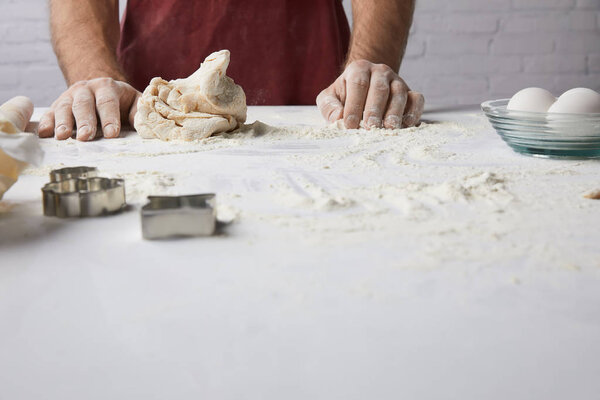cropped image of chef standing at table with dough