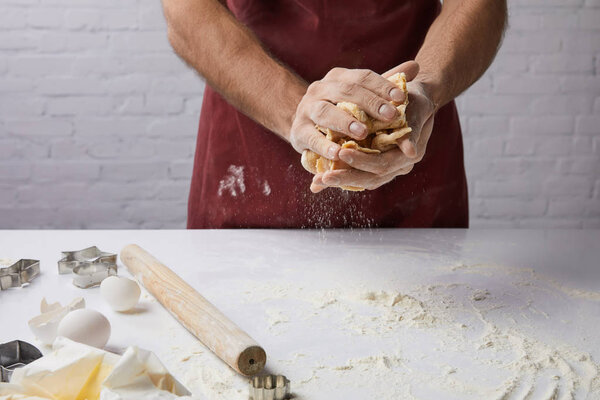 cropped image of chef kneading dough in hands 