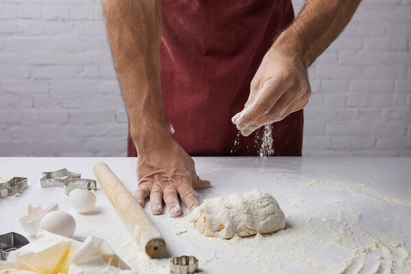 cropped image of chef adding flour to dough